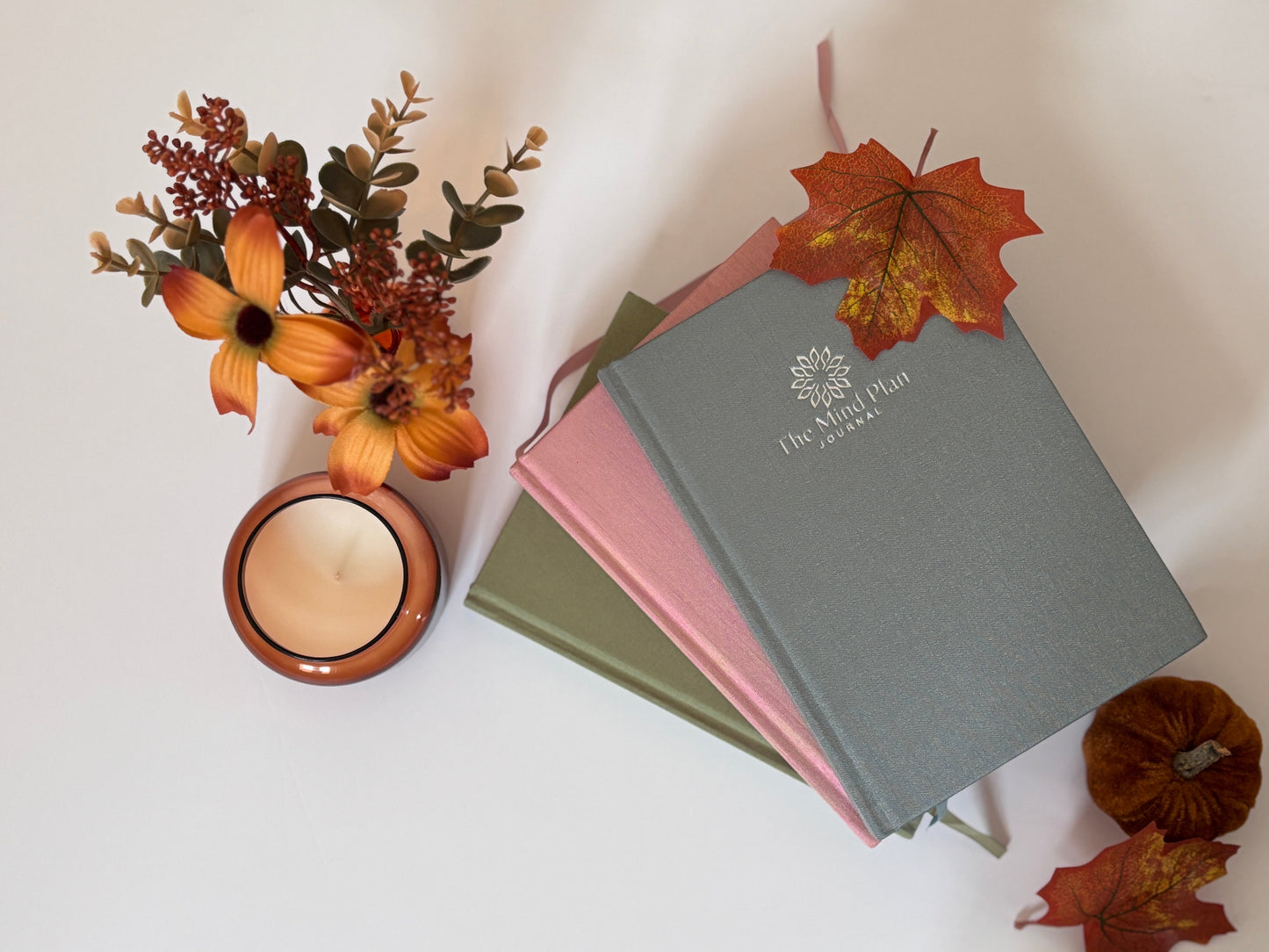 Stack of books with a candle and flowers on a light background