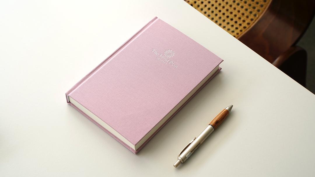 Close-up photo of The Mind Plan Journal in pink Linen on a soft background, minimal and elegant